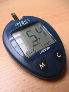 A close-up of a glucometer placed on a brown surface.