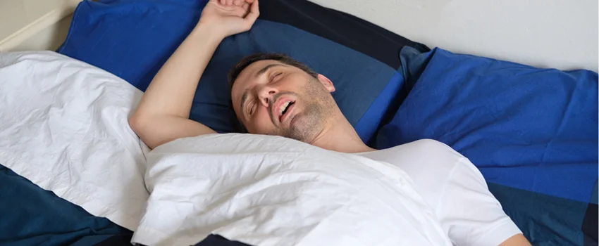 Man snoring while sleeping in bed.