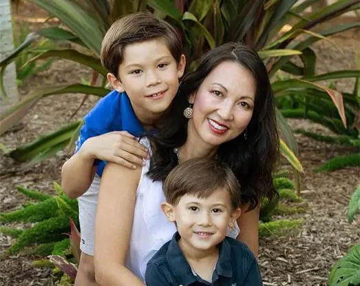 A close-up of Doctor Nancy Nguyen and her two sons against a garden plant in the background.
