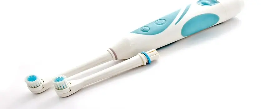 A close-up of a blue electric toothbrush and an electric toothbrush head on a white surface.