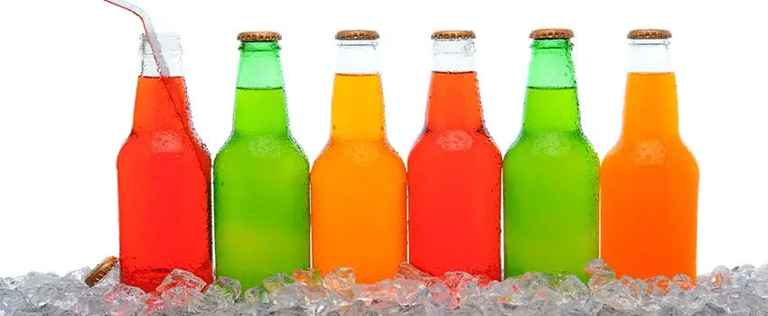 A close-up of six different soda bottles on top of ice cubes.